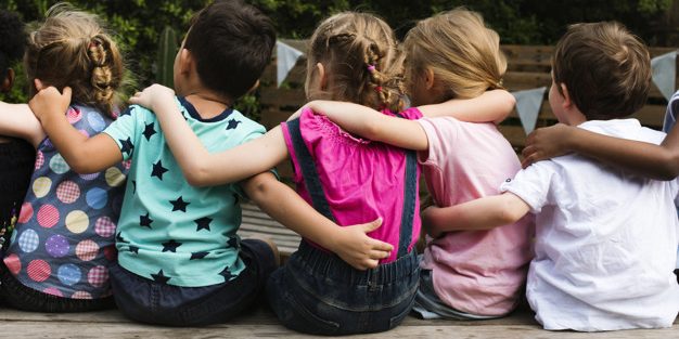 Group of kindergarten kids friends arm around sitting together